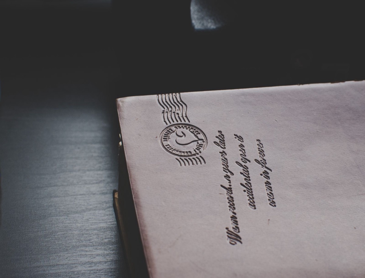 A pale paper item embossed with a postmark and script lettering on a dark surface