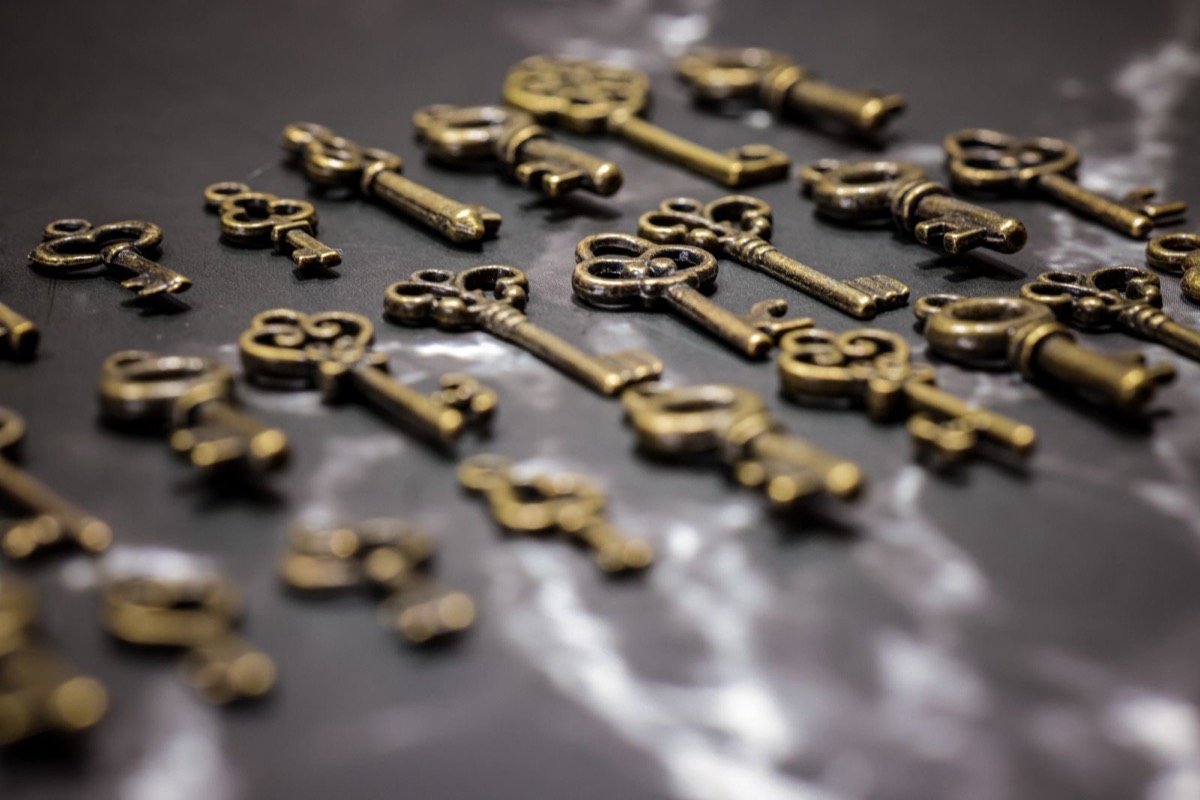 Rows of ornate antique brass keys laid out on a dark marbled surface
